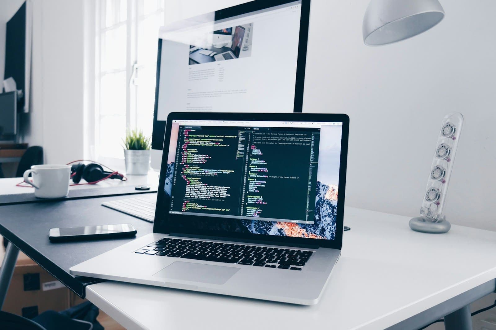 Web developer workspace with a laptop showing code for a responsive website